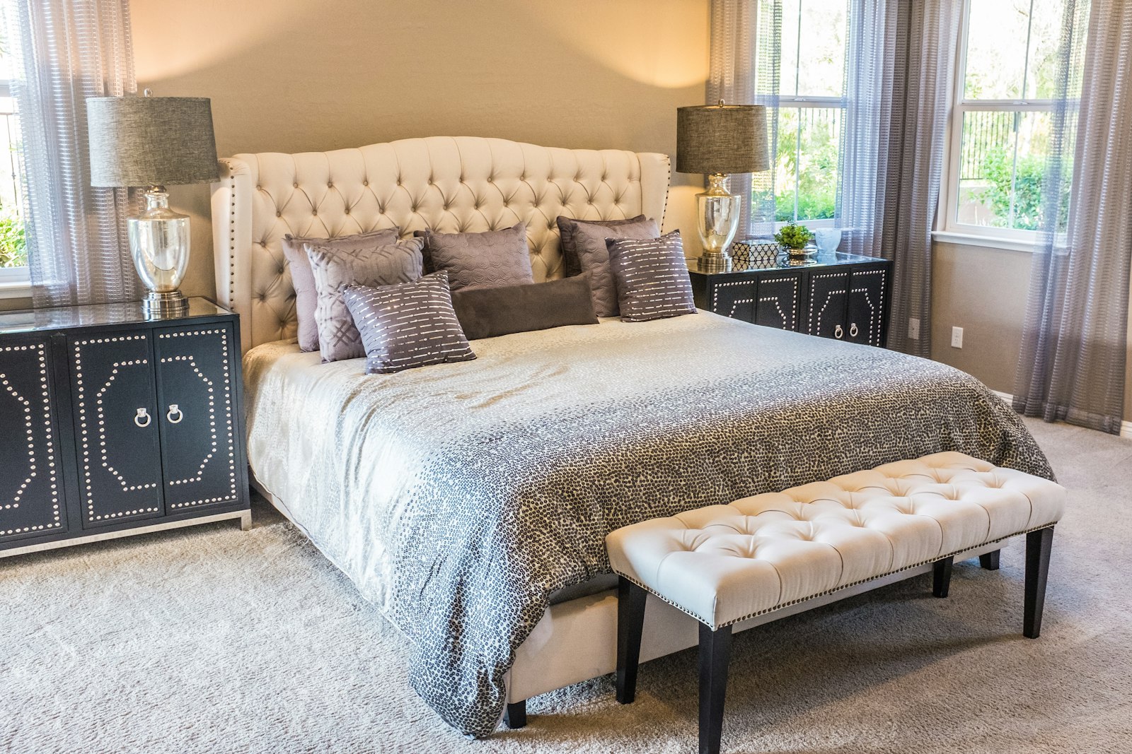 Bright bedroom with upholstered headboard, twin nightstands with lamps, and decorative pillows